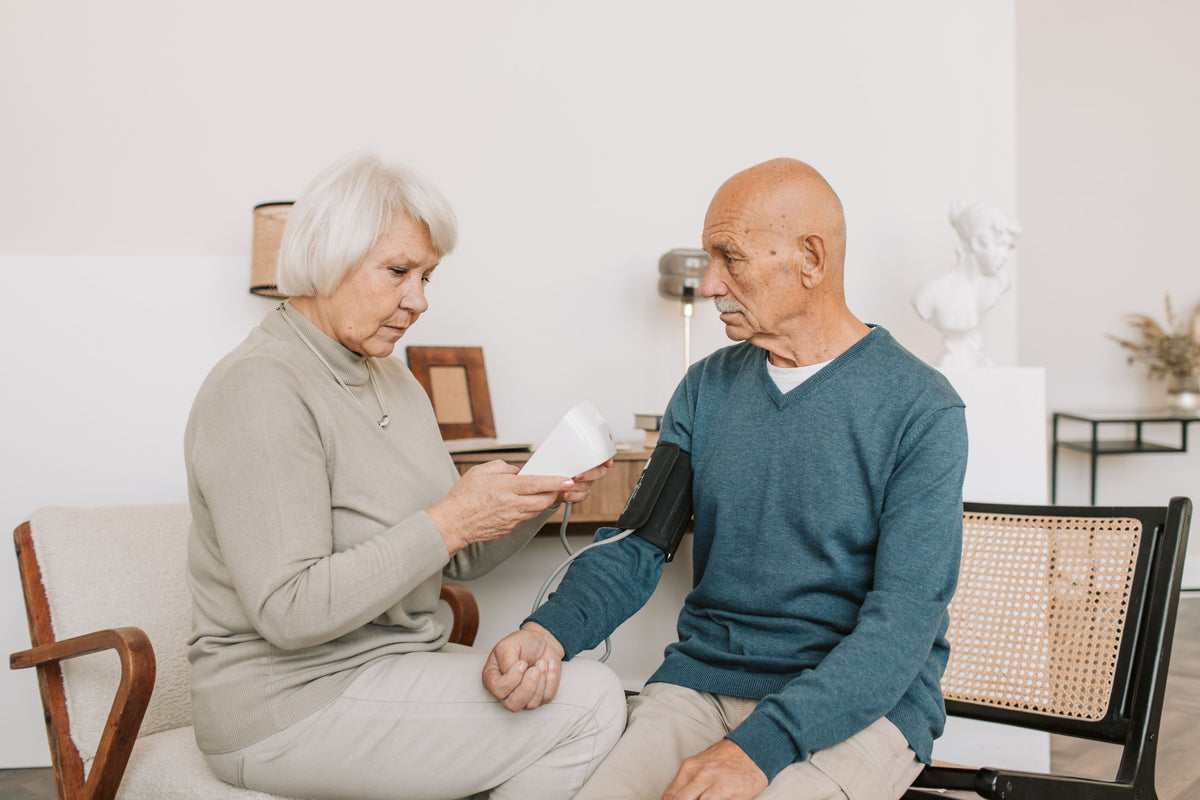 Senior couple checking blood pressure with an automatic BP machine at home